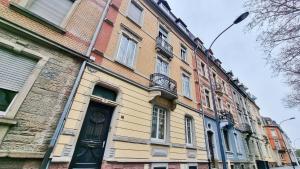 un edificio amarillo con una puerta negra en una calle en Le Serenity - Spacieux et Confortable - Relax BNB, en Mulhouse