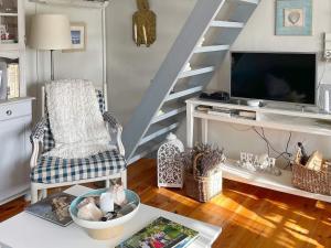 ein Wohnzimmer mit einer Treppe, einem TV und einem Stuhl in der Unterkunft Holiday home TOMELILLA V in Tomelilla