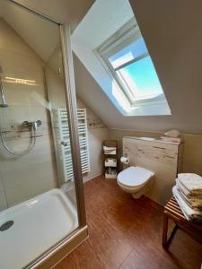 ein Bad mit einer Dusche, einem WC und einem Dachfenster in der Unterkunft Haus Dollart in Borkum
