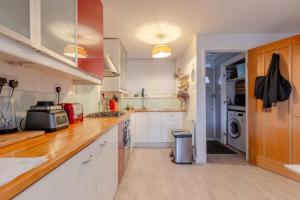 a kitchen with white cabinets and wooden counter tops at Stunning 1BD Flat w Garden area Kentish Town! in London