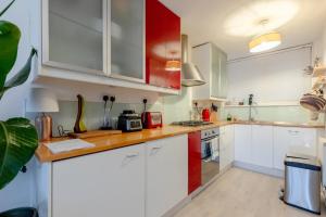 a kitchen with white cabinets and red accents at Stunning 1BD Flat w Garden area Kentish Town! in London
