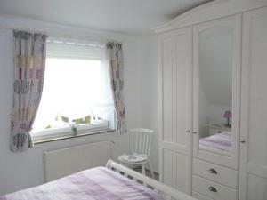 um quarto branco com uma cama e uma janela em Holiday apartment Am Elbdeich 2 em Jork