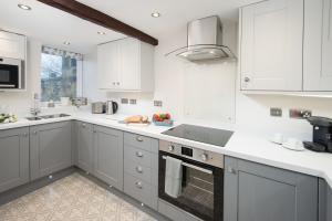 a kitchen with white cabinets and a stove top oven at Castle Retreat - luxury apartment opposite Alnwick Castle in Alnwick