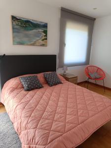 ein Schlafzimmer mit einem großen Bett mit einer rosa Decke in der Unterkunft Apartamento Playa Ladeira in Baiona