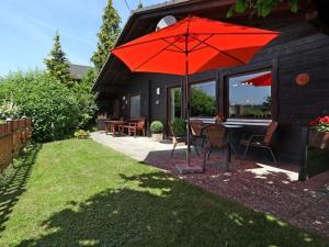 una sombrilla roja sentada en el patio de una casa en Appealing apartment in Grafenau en Haus im Wald