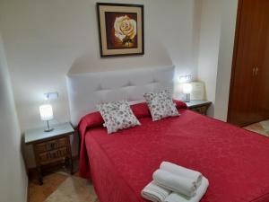 a bedroom with a red bed with two lamps and towels at Hostal San Roque in Guadalajara +67 photos