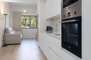 a white kitchen with a black oven and a couch at ApartUP Turia River Park in Valencia