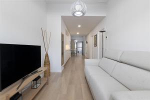 a living room with a white couch and a flat screen tv at ApartUP Turia River Park in Valencia