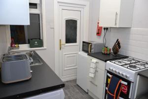 a kitchen with white cabinets and a stove top oven at Salisbury - New 3br home, wifi, parking, sleeps 6, near Liverpool city centre in Birkenhead