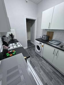 a white kitchen with a stove and a microwave at Salisbury - New 3br home, wifi, parking, sleeps 6, near Liverpool city centre in Birkenhead