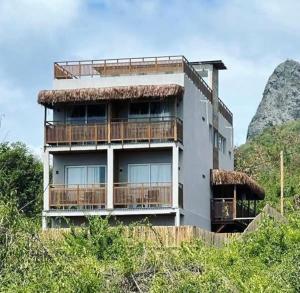 a building on a hill with a mountain in the background at Pousada Divino Morro in Fernando de Noronha