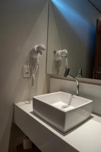 lavabo blanco en el baño con espejo en Pousada Divino Morro, en Fernando de Noronha