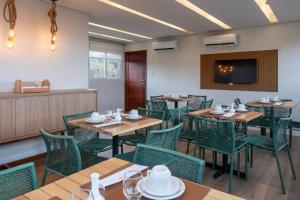um restaurante com mesas de madeira e cadeiras verdes em Pousada Divino Morro em Fernando de Noronha