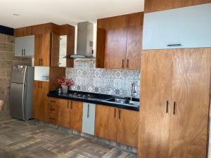 La cuisine est équipée d'armoires en bois et d'un réfrigérateur en acier inoxydable. dans l'établissement Casa de descanso, à León