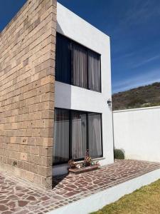 une maison blanche avec des fenêtres noires sur un mur de briques dans l'établissement Casa de descanso, à León