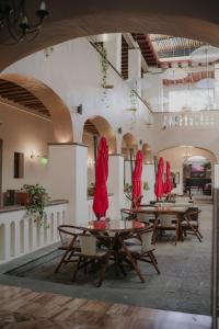 ein Restaurant mit Tischen, Stühlen und roten Sonnenschirmen in der Unterkunft Hotel Casa Antigua in Oaxaca de Juárez