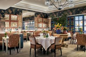 Warren Street Hotel في نيويورك: غرفة طعام مع طاولات وكراسي وجدار زهري