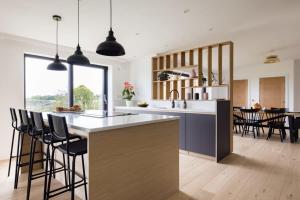 a kitchen with a large island with bar stools at Stunning 5 Bedroom New Build with Amazing Views! in Bath