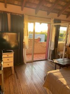 a bedroom with a flat screen tv and a balcony at Casa golf en las sierras de Cordoba in Cordoba