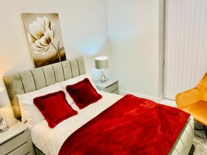 a bedroom with a bed with two red pillows at Icare Lodge Ltd,Safwaan House. in Barking