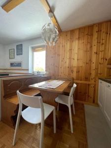 una cucina con tavolo, due sedie e un lampadario a braccio di Maison Le Pommier a Morgex