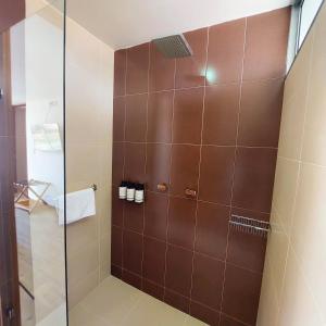 ein Bad mit einer Dusche mit braunen Fliesen in der Unterkunft Samakwā Hotel Boutique in Paipa