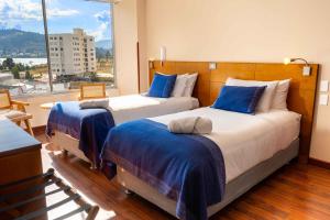 2 Betten in einem Zimmer mit einem großen Fenster in der Unterkunft Samakwā Hotel Boutique in Paipa