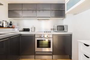 a kitchen with stainless steel appliances and a microwave at Welcoming Flat with Sauna - Paddington in London