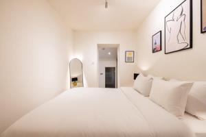 a white bedroom with a large bed with white pillows at Welcoming Flat with Sauna - Paddington in London