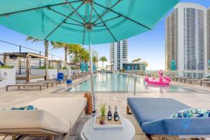 uma piscina com um guarda-sol azul e cadeiras e uma piscina em Luxury Coastal Stay, Bay View, Free Valet Parking em Hollywood