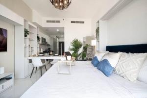 a bedroom with a large white bed and a kitchen at Dubai Sleek & Cozy Space in Dubai