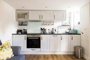 a kitchen with white cabinets and a stove top oven at The Lavender Folly - Cosy Accommodation Alresford in New Alresford