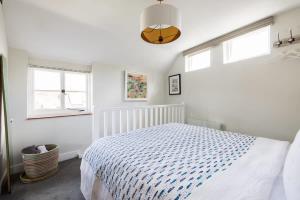 a white bedroom with a bed and two windows at The Lavender Folly - Cosy Accommodation Alresford in New Alresford