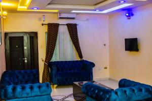 a living room with two blue chairs and a tv at E45 Hotels and Suites in Owerri