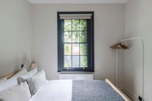 1 dormitorio con cama blanca y ventana en Georgian Townhouse with Sun Terrace & Garden en Londres