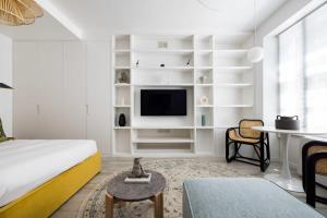 Habitación blanca con cama, escritorio y TV. en Light-filled Studio with AC - Earl's Court, en Londres