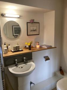a bathroom with a sink and a mirror at Brook Farm Cottage in Brackley