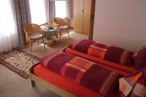グリンデルワルトにあるホテル ブルムリサルプのベッド2台、テーブルと椅子が備わるホテルルームです。