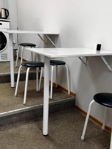 a white table with four stools under it in a kitchen at Sunny Hostel Nurmakova in Almaty