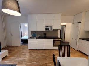 a kitchen with white cabinets and a table and a room at Home Inn RSG19 in Stockholm