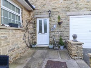 a stone house with a white door and potted plants at Foxholes Lodge in Settle