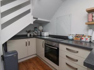 a kitchen with white cabinets and black counter tops at Foxholes Lodge in Settle