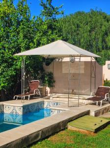 - un parasol blanc assis à côté d'une piscine avec 2 chaises dans l'établissement Departamento los lapachos, à Villa Allende