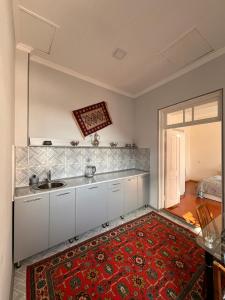 a kitchen with white cabinets and a red rug at Nuray's House in Sheki