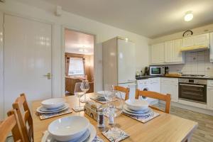 - une cuisine avec une table en bois, des assiettes et des verres à vin dans l'établissement Comfortable 3 bed house in Chelmsford, à Chelmsford