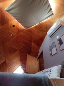 Pokój z łóżkiem i drewnianym sufitem w obiekcie Domo guidaí w mieście Tacuarembó