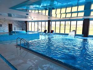 a large swimming pool with people sitting in chairs in it at Modern Loft SPA in Dziwnów