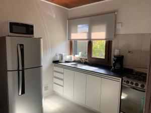 a white kitchen with a refrigerator and a window at CyclosApart in Esquel