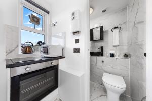 a bathroom with a toilet and a sink and a window at Cosy Studio Flat - Central London NW3 - Transport Links Euston, King Cross, Finchley Road Station in London