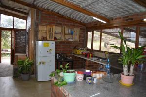 a kitchen with a white refrigerator and a brick wall at Casa de campo independiente sector Chachimbiro –Urcuqui in Ibarra